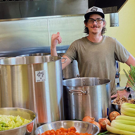 Chef stading behind table of veggies and pots