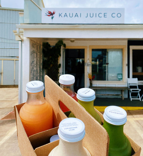 A box of juices in front of a Kauai Juice storefront