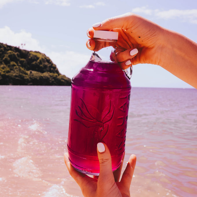 Hands holding bottle of kombucha on the beach