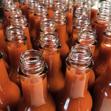 A bunch of open bottles of hot sauce