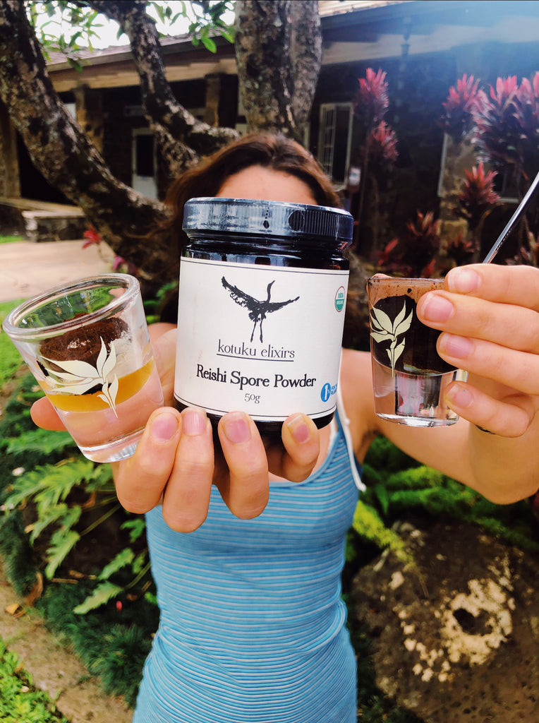 woman holding two shot glasses and jar of reishi spore powder